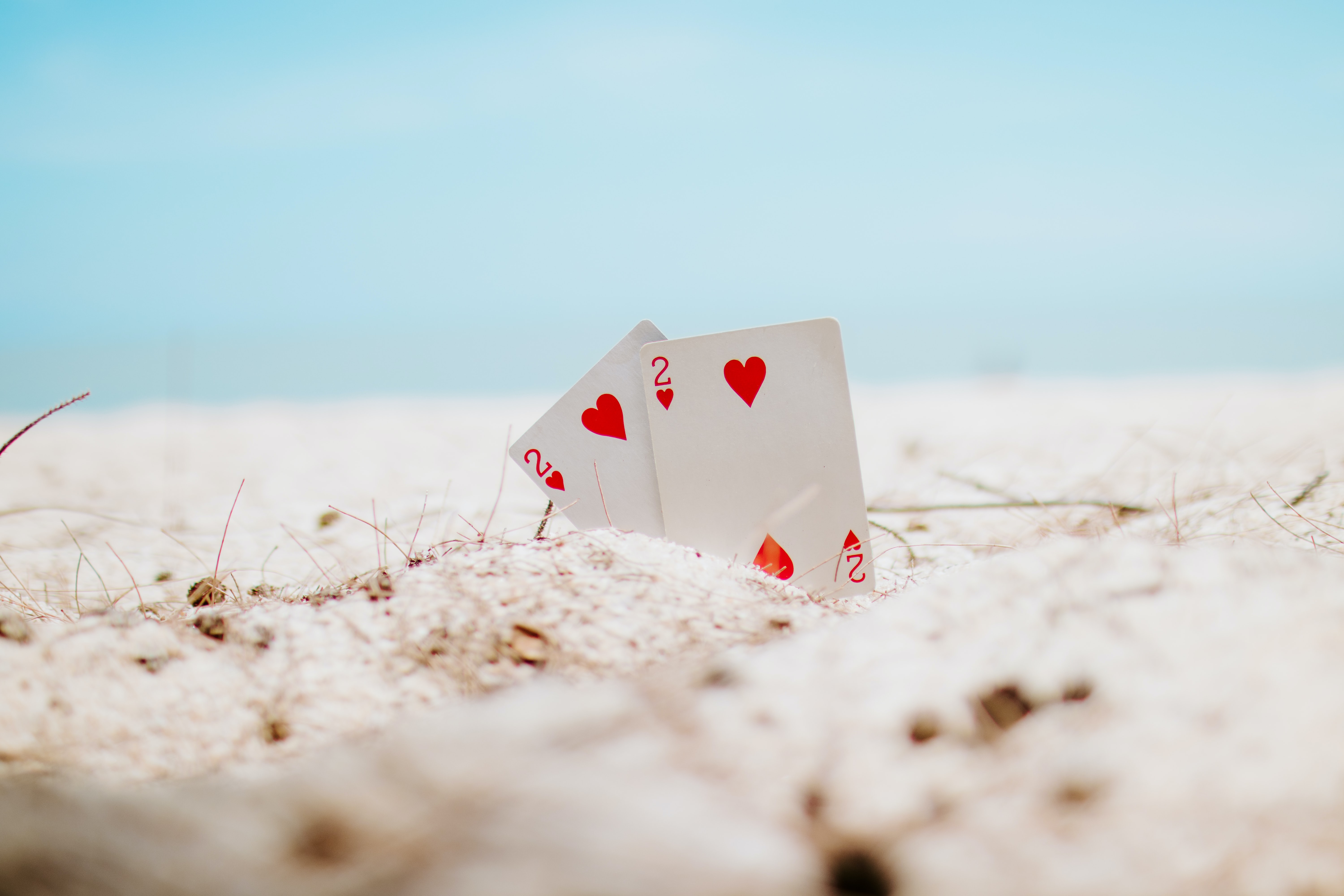 Zwei Karten mit zwei Herzen, die im Sand am Strand liegen. Steht sinnbildlich für die doppelte Chance von KI-Kompetenzen.